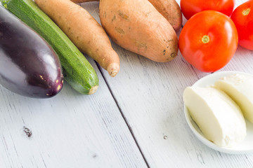 Collection of fresh vegetables and mozzarella on a kitchen table.