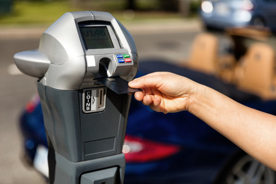 Hand putting credit card into parking meter for time