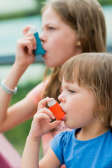 Girls having asthma using asthma inhaler for being healthy - shallow depth of field 