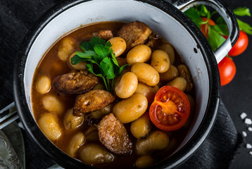 Hot baked beans with tomato and parsley in pot