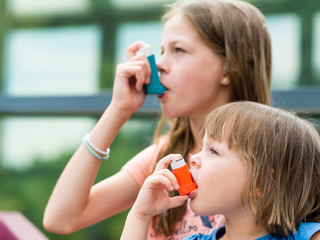 Girls having asthma using asthma inhaler for being healthy - shallow depth of field 