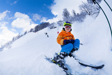 Fototapeta na wymiar Child with ski and wearing mask sit in snow