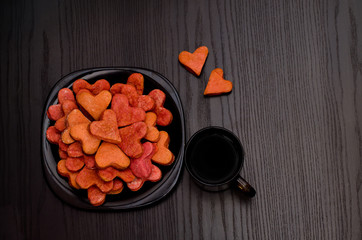Red heart-shaped cookies on a black plate, coffee mug , Valentine's Day