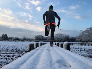 Man running on fresh snow covered early morning trail 
