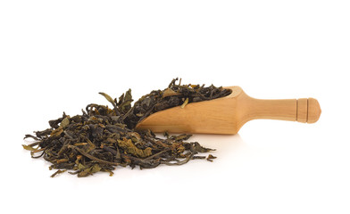Wooden spoon over dry green tea leaves