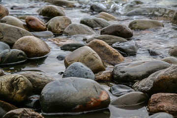 Obraz premium stones on lake shore with differente colors