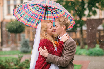 Young beautiful couple bride and groom in the snow with an umbrella