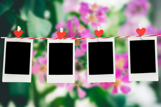 4 Blank instant photo and red clippaper heart hanging on the clothesline with pink flower nature background.Designer concept.