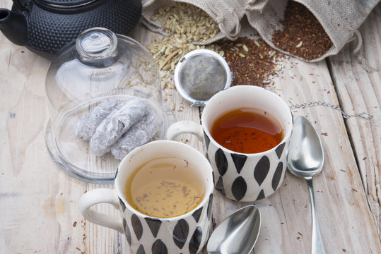 two cups 1 black tea rooibos and other fennel with teapot in the