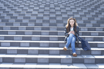 Young women are looking at the smartphone sitting on the stairs