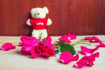 Pink rose and teddy bear on wood background Valentine's Day