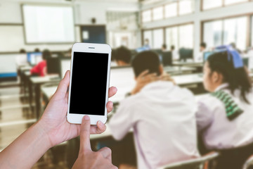 Hands woman are holding touch screen smart phone,tablet on blurred Defocused student study computer classroom  background.