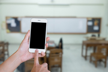 Hands woman are holding touch screen smart phone,tablet on blurred classroom nobody student and teacher  background.