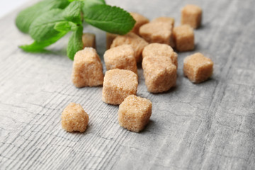 Pile of brown sugar cubes and stevia  on grey wooden background