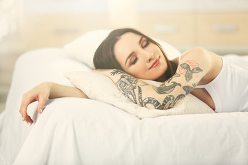 Attractive woman with tattoo lying on the bed