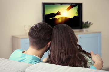 Young couple watching TV on a sofa at home