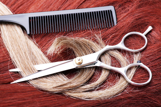 Hairdresser's scissors with comb and varicolored strands of hair, close up