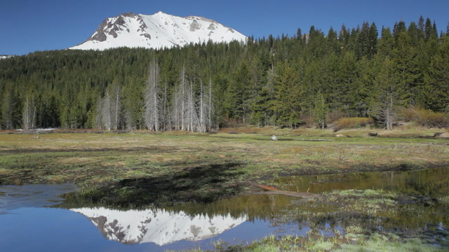 Panning view of Lassen Peak reflecting in Hat Lake, in Lassen Volcanic National Park, California.