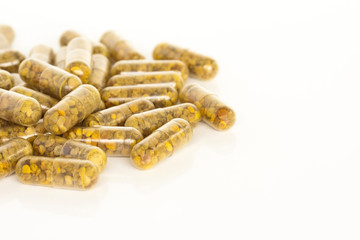 Bee Pollen Supplements. A pile of bee pollen supplement capsules isolated on a white background.