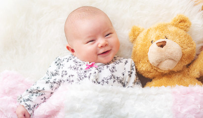 Newborn baby girl on her blanket with her teddy bear
