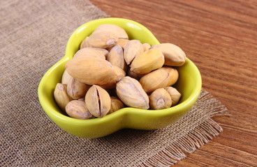 Pistachio nuts in bowl on wooden table, healthy eating