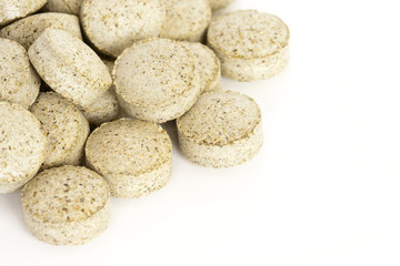 Sea Kelp Vitamin Supplements. A pile of sea kelp vitamin supplement tablets isolated on a white background.