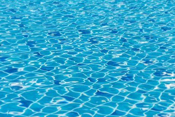 blurred of blue swimming pool with sunny reflections