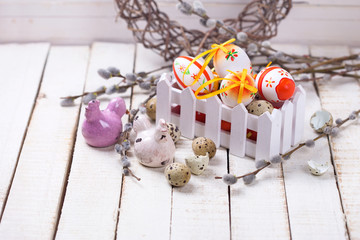 Decorative  easter eggs in box, hens  and  willow  branches on w