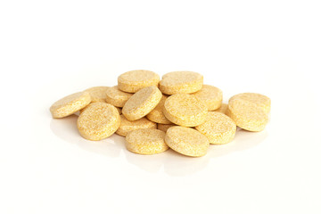 Vitamin C Tablet Supplements. A pile of vitamin C supplement tablets isolated on a white background.