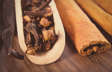 Vintage photo, Closeup of cloves, fragrant vanilla and cinnamon on wooden surface plank