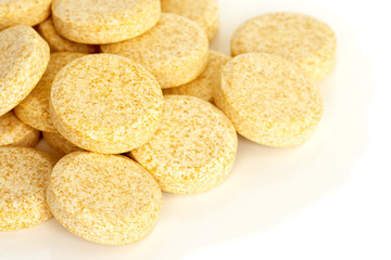 Vitamin C Tablet Supplements. A pile of vitamin C supplement tablets isolated on a white background.