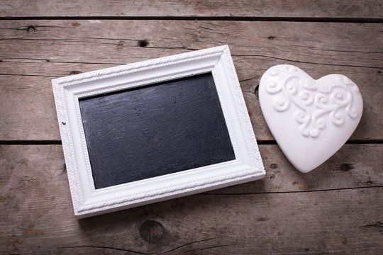 White decorative  heart and empty blackboard on aged wooden back