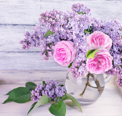 Bouquet of lilac flowers and roses in glass bottle