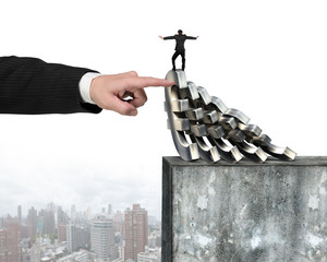 Hand stopping Euro money domino falling with man balance it