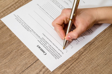 female hand signing a contract  on desk