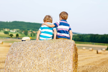 Two little children and friends with hay stack or bale
