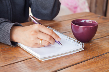 Woman hand with pen writing on notebook