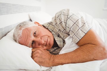 Sick senior man lying on bed
