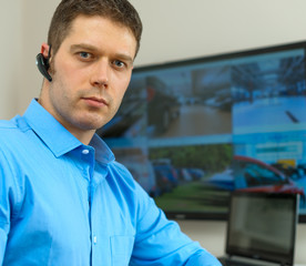 Security guard monitoring video in security room.