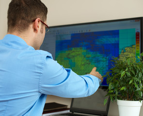 Handsome male meteorologist working with touchscreen.