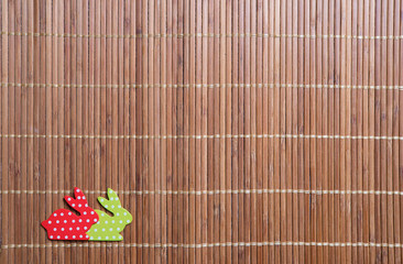 Two decorative colorful bunnies on rattan pad background