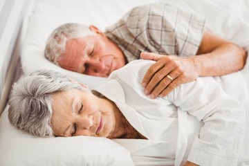 Senior couple sleeping on bed