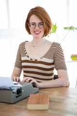 smiling hipster woman typing on her typewriter