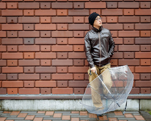An Asian Man in a Brown Jacket with a Small Notebook 