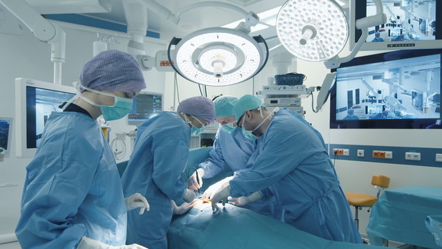 Medical Team Performing Surgical Operation in Bright Modern Operating Room. Shot on RED Cinema Camera.