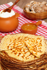Pancake week. Pancakes, honey and a pot with sour cream.