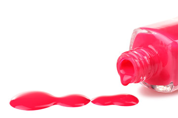 pink nail Polish in the bottle and a little bit spilled on a white isolated background