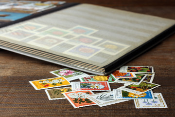 open the album with a very large and expensive collection of stamps on wooden brown table near to a bunch of other more valuable stamps