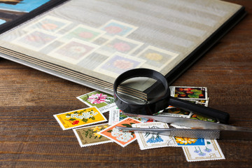 open the album with a very large and expensive collection of stamps on wooden brown table near to a...