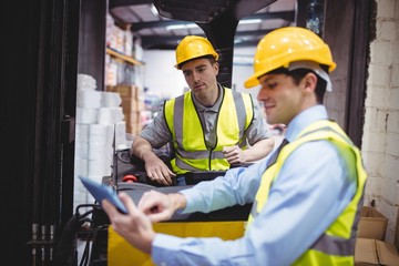 Warehouse worker talking with forklift driver